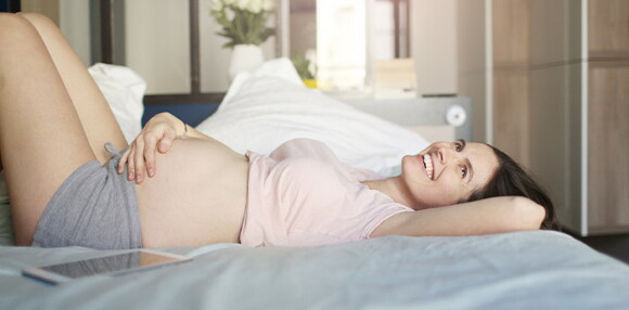 Mujer embarazada recostada en la cama